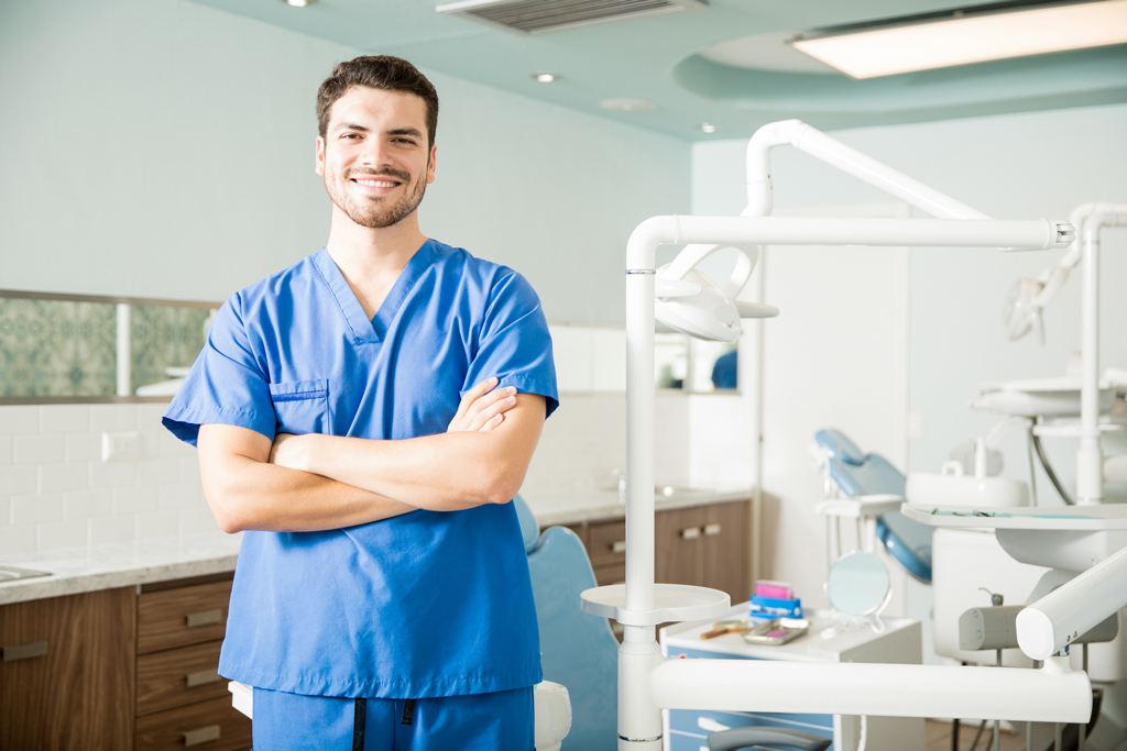 Smiling Dentist Standing In Operating Room Surrounded By Dental Technology